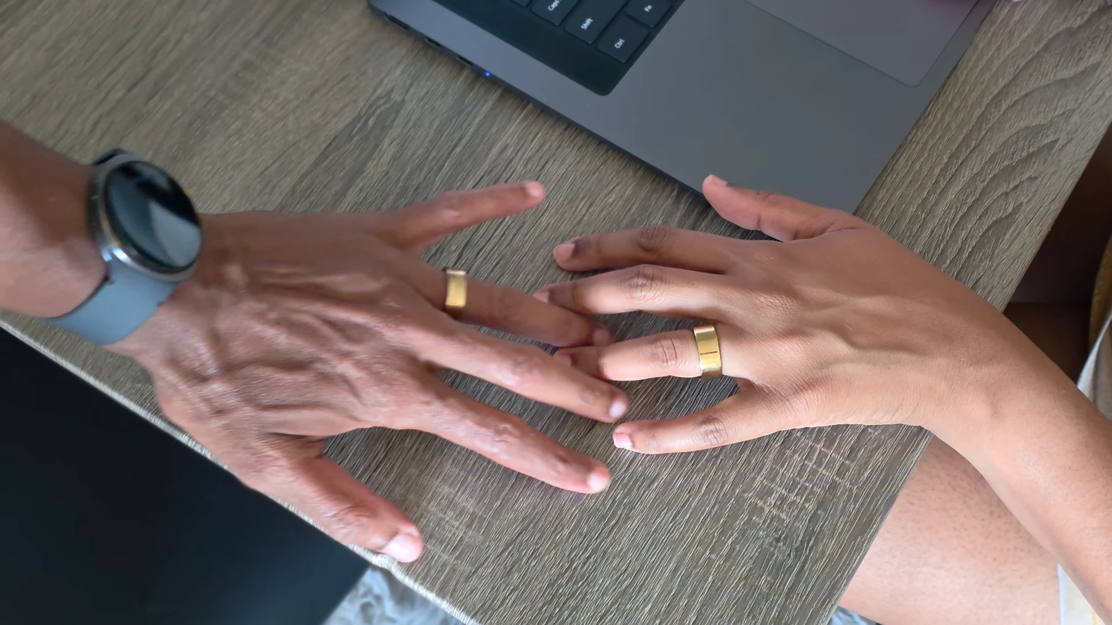 A smartwatch worn on the wrist alongside smart rings worn on the fingers, showing both devices used together