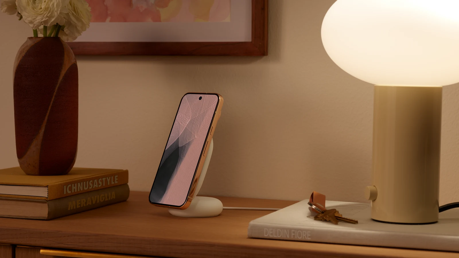 Pixel 11 Pro docked upright on a Pixelsnap stand on a bedside table beside a lamp